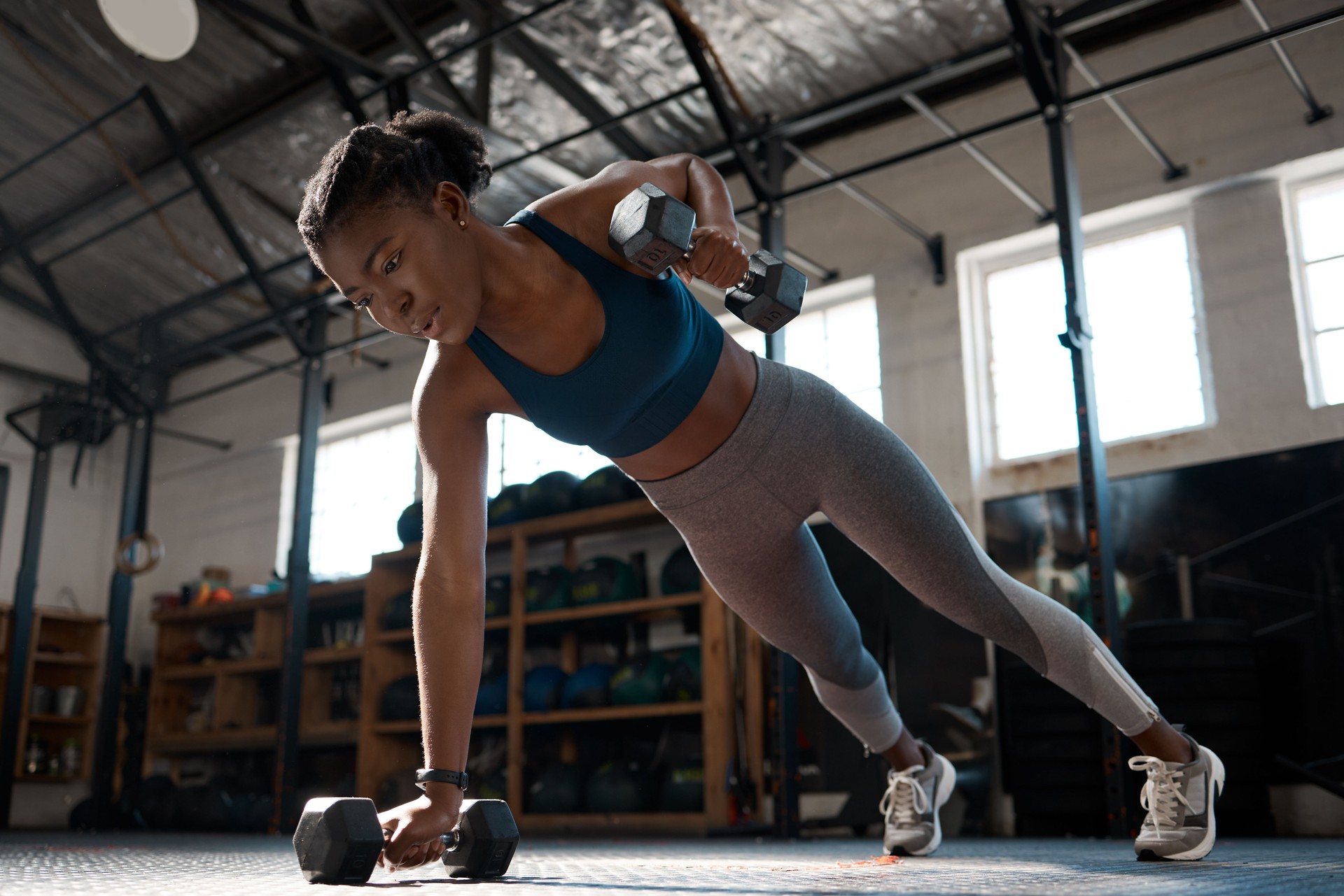 Low angle shot of an attractive and athletic young woman working out with dumbbells in the gym